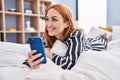 Young caucasian woman using smartphone lying on bed at bedroom Royalty Free Stock Photo