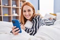 Young caucasian woman using smartphone lying on bed at bedroom Royalty Free Stock Photo