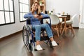 Young caucasian woman using smartphone sitting on wheelchair at home Royalty Free Stock Photo