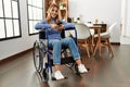 Young caucasian woman using smartphone sitting on wheelchair at home Royalty Free Stock Photo