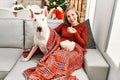 Young caucasian woman watching movie sitting with dog by christmas tree at home Royalty Free Stock Photo