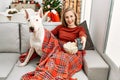 Young caucasian woman watching movie sitting with dog by christmas tree at home Royalty Free Stock Photo
