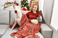 Young caucasian woman watching movie sitting with dog by christmas tree at home Royalty Free Stock Photo