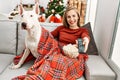 Young caucasian woman watching movie sitting with dog by christmas tree at home Royalty Free Stock Photo