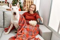 Young caucasian woman watching movie sitting with dog by christmas tree at home Royalty Free Stock Photo