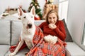 Young caucasian woman watching movie sitting with dog by christmas tree at home Royalty Free Stock Photo