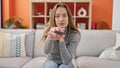 Young caucasian woman watching tv sitting on sofa at home Royalty Free Stock Photo