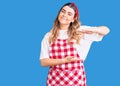 Young caucasian woman wearing apron gesturing with hands showing big and large size sign, measure symbol Royalty Free Stock Photo