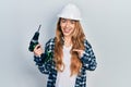 Young caucasian woman wearing architect hardhat using drill smiling happy pointing with hand and finger Royalty Free Stock Photo