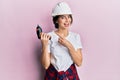 Young caucasian woman wearing architect hardhat using drill smiling happy pointing with hand and finger Royalty Free Stock Photo