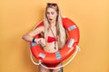 Young caucasian woman wearing bikini and holding lifeguard float looking at the watch time worried, afraid of getting late Royalty Free Stock Photo
