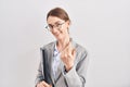 Young caucasian woman wearing business clothes and glasses beckoning come here gesture with hand inviting welcoming happy and Royalty Free Stock Photo