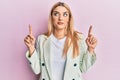 Young caucasian woman wearing business clothes pointing up with fingers smiling looking to the side and staring away thinking Royalty Free Stock Photo