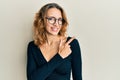 Young caucasian woman wearing business shirt and glasses cheerful with a smile of face pointing with hand and finger up to the Royalty Free Stock Photo