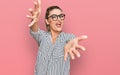 Young caucasian woman wearing business shirt and glasses looking at the camera smiling with open arms for hug Royalty Free Stock Photo