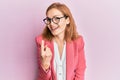Young caucasian woman wearing business style and glasses beckoning come here gesture with hand inviting welcoming happy and Royalty Free Stock Photo