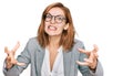 Young caucasian woman wearing business style and glasses shouting frustrated with rage, hands trying to strangle, yelling mad