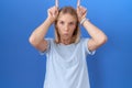 Young caucasian woman wearing casual blue t shirt doing funny gesture with finger over head as bull horns Royalty Free Stock Photo