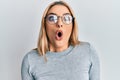 Young caucasian woman wearing casual clothes and glasses scared and amazed with open mouth for surprise, disbelief face