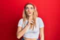 Young caucasian woman wearing casual white t shirt thinking concentrated about doubt with finger on chin and looking up wondering Royalty Free Stock Photo