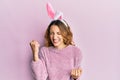 Young caucasian woman wearing cute easter bunny ears celebrating surprised and amazed for success with arms raised and eyes closed