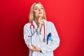 Young caucasian woman wearing doctor uniform and stethoscope looking confident at the camera with smile with crossed arms and hand Royalty Free Stock Photo