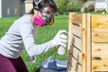 A young caucasian woman wearing face mask safety goggles and gloves is spray staining