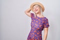 Young caucasian woman wearing flowers dress and summer hat smiling confident touching hair with hand up gesture, posing attractive Royalty Free Stock Photo