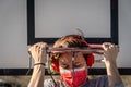 Young Caucasian woman wearing a mask with headphones and phone dunking on basketball ring