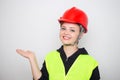 Young caucasian woman wearing red safety hard hat and reflective vest, smiling