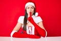 Young caucasian woman wearing santa claus costume asking to be quiet with finger on lips Royalty Free Stock Photo