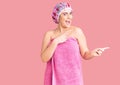 Young caucasian woman wearing shower cap and towel smiling and looking at the camera pointing with two hands and fingers to the Royalty Free Stock Photo