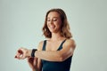 Young caucasian woman in sports bra and fitness tracker smiling while looking down in studio Royalty Free Stock Photo