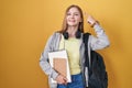 Young caucasian woman wearing student backpack and holding books smiling pointing to head with one finger, great idea or thought, Royalty Free Stock Photo