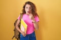 Young caucasian woman wearing student backpack and holding books surprised pointing with finger to the side, open mouth amazed Royalty Free Stock Photo