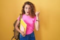 Young caucasian woman wearing student backpack and holding books surprised pointing with hand finger to the side, open mouth Royalty Free Stock Photo