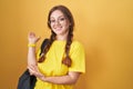 Young caucasian woman wearing student backpack over yellow background inviting to enter smiling natural with open hand Royalty Free Stock Photo