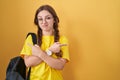 Young caucasian woman wearing student backpack over yellow background pointing to both sides with fingers, different direction