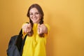 Young caucasian woman wearing student backpack over yellow background pointing to you and the camera with fingers, smiling Royalty Free Stock Photo