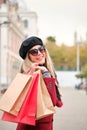 Young caucasian woman wearing sunglasses holding shopping bags in winter. Royalty Free Stock Photo