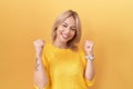 Young caucasian woman wearing yellow sweater very happy and excited doing winner gesture with arms raised, smiling and screaming