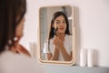 Young caucasian woman wears white t-shirt uses ball roller in front of mirror in her bedroom.