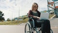 Young caucasian woman in the wheelchair using laptop. Train passing in the background Royalty Free Stock Photo