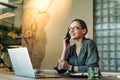 Young caucasian woman working at her desk with laptop and talking on phone Royalty Free Stock Photo