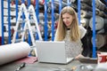 Young caucasian woman working with her laptop in a textile factory Royalty Free Stock Photo