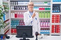 Young caucasian woman working at pharmacy drugstore cheerful with a smile of face pointing with hand and finger up to the side Royalty Free Stock Photo