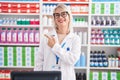 Young caucasian woman working at pharmacy drugstore cheerful with a smile of face pointing with hand and finger up to the side Royalty Free Stock Photo