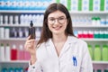 Young caucasian woman working at pharmacy drugstore holding serum looking positive and happy standing and smiling with a confident Royalty Free Stock Photo