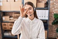 Young caucasian woman working at small business ecommerce wearing headset smiling happy doing ok sign with hand on eye looking Royalty Free Stock Photo