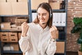 Young caucasian woman working at small business ecommerce wearing headset very happy and excited doing winner gesture with arms Royalty Free Stock Photo